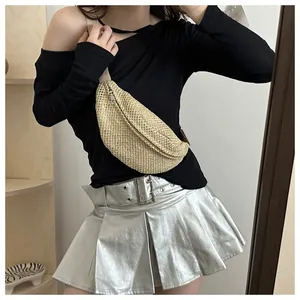 Detailed view of hand-woven straw chest bag with adjustable strap worn by model