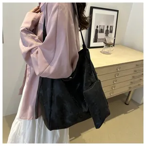 Vista laterale di una grande borsa tote nera con pochette abbinata sul modello