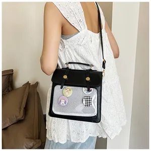 Detail einer schwarzen PU-Tasche mit transparenter Netztasche und bunten Cartoon-Ansteckern