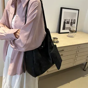 Borsa tote nera minimalista con piccola pochette mostrata sul modello in interni