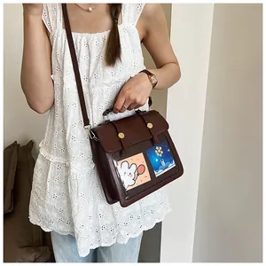Detail der braunen Ledertasche mit transparenten Fächern und niedlichen Motivkarten