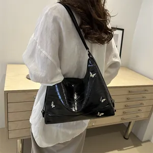 Minimalist black patent leather shoulder bag with crocodile pattern and silver butterfly buckles