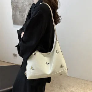 Minimalist cream shoulder bag with embossed texture and metal butterfly accents