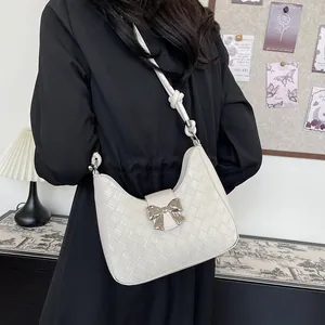 White woven crescent shoulder bag with silver bow clasp and knotted strap detail