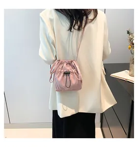 Detail of pink nylon bucket bag with drawstring and adjustable strap on model