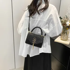 Sac bandoulière minimaliste noir pour femmes avec paillettes et pompon doré élégant