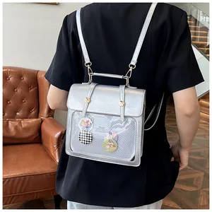 Detail eines silbernen Metall-Rucksacks mit Netzfach und niedlichen Cartoon-Badges-Deko