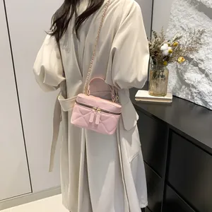 Pink quilted mini bucket bag with chain strap shown on model in a modern interior