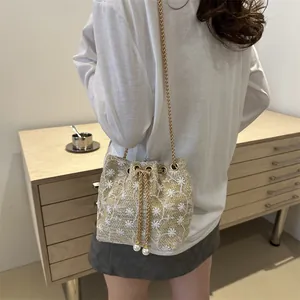 Minimalist woven bucket bag with white floral embroidery and gold chain strap for women