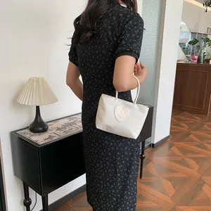 Minimalist white tote bag with heart smiley patch held by model in floral dress
