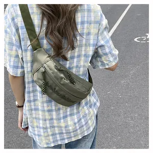Close-up of green nylon crossbody bag featuring embossed letters and woven zipper puller