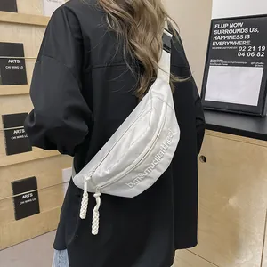 White satin chest bag with letter embroidery and woven zipper pulls shown on model