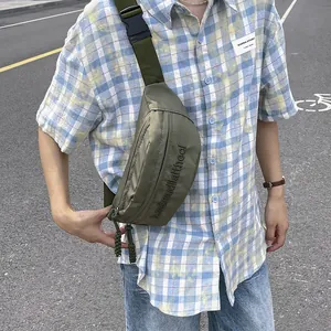 Army green nylon chest bag with adjustable strap and buckle shown on model in street view