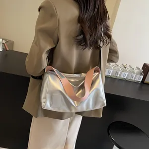 Silver metallic pillow shoulder bag with pink strap worn by model in a modern room