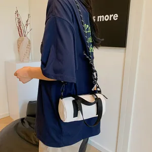 Minimalist white cylinder crossbody bag with contrasting black straps for casual styling