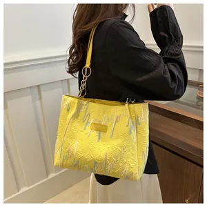 Détail du sac cabas jaune avec broderies colorées et texture de tissu gaufrée