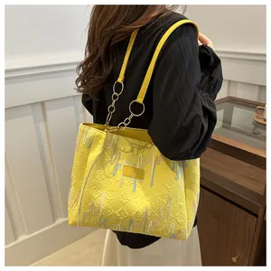 Détail du sac cabas jaune en tissu gaufré avec broderies colorées et chaînette