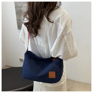 Vue arrière du sac bandoulière en toile bleu marine avec sangle colorée et étiquette