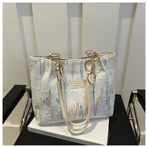Détail du sac cabas crème avec broderies zigzag colorées et textures gaufrées élégantes