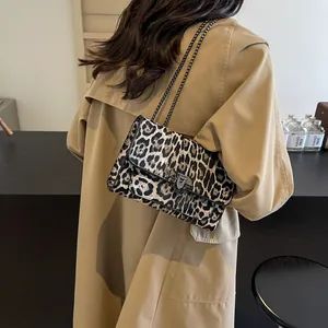 Sac bandoulière imprimé léopard avec chaîne en métal porté par un mannequin en trench