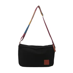 Sac bandoulière minimaliste en toile noire avec bandoulière rayée colorée pour femme