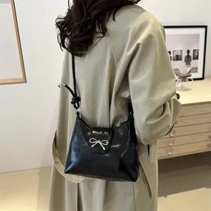 Sac seau noir brillant minimaliste avec nœud argenté et bandoulière réglable