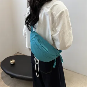 Minimalist cyan canvas chest bag with woven zipper puller shown on model back