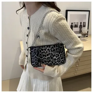 Detailed view of leopard print crossbody bag with silver chain and studded trim accents