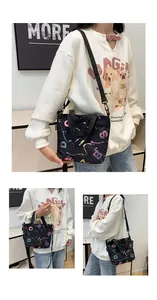 Detail showing black graffiti crossbody bag with colorful lettering and nylon strap worn by model