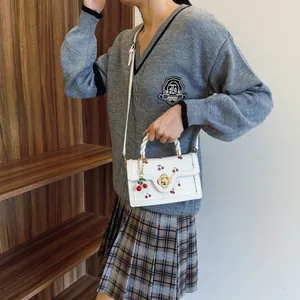 Sac bandoulière blanc à motif cerise avec fermoir fleur dorée et poignée tressée