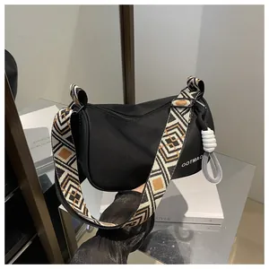 Détail du sac bandoulière demi-lune noir avec large sangle jacquard à motifs géométriques