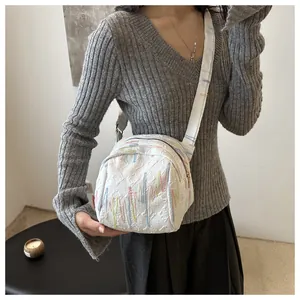 Gros plan du sac bandoulière blanc avec texture gaufrée et broderies colorées élégantes