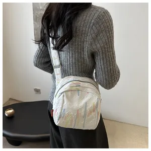 Détail du sac bandoulière blanc avec broderies ondulées colorées et textures gaufrées