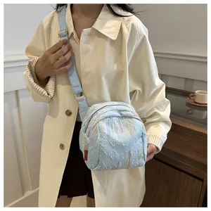 Détail du sac bandoulière bleu clair avec texture gaufrée 3D et broderies colorées
