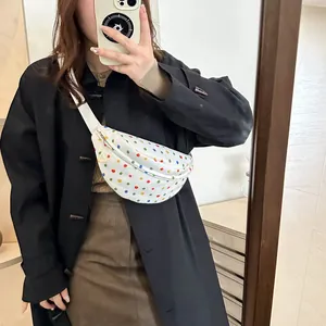 Minimalist white crossbody bag with colorful polka dots and adjustable strap in use
