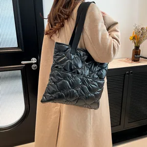 Minimalist black quilted tote bag with large diamond stitching and a glossy nylon finish