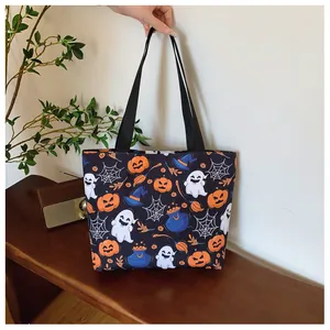 Detail view of Halloween canvas tote bag with ghost and pumpkin patterns on black fabric