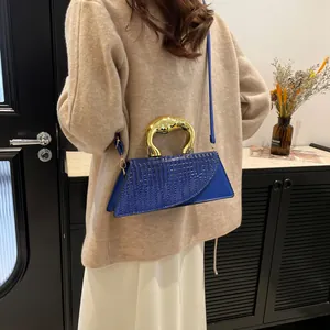 Royal blue handbag with gold circular handle and crocodile texture flap, shown on model