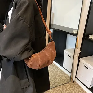 Minimalist brown suede croissant crossbody bag with elegant knotted shoulder strap detail