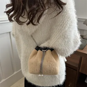 Furry bucket bag in light khaki with silver chain strap shown on a model
