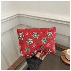 Close-up of a festive red Christmas clutch bag with snowflake patterns held by hand