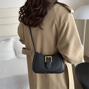 Sac hobo noir minimaliste avec boucle dorée présenté de dos sur l'épaule d'un mannequin