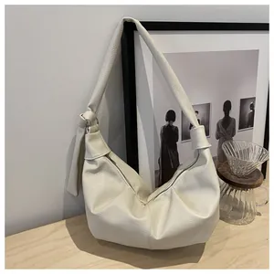 Close-up of cream leather tote showing fine litchi texture and knotted strap detail