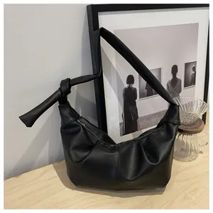 Detail of black lychee grain leather underarm bag with unique knotted strap design