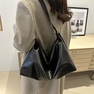 Retro black leather tote bag with gold hardware worn by model in a stylish indoor setting
