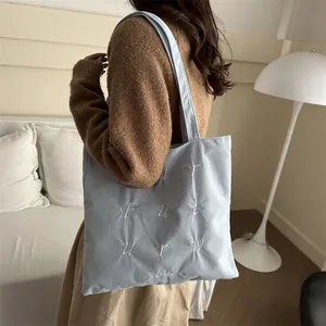 Light blue corduroy tote bag with white embroidery shown in a modern interior setting