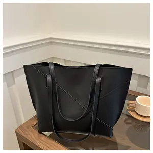 Dettaglio borsa tote in pelle nera con eleganti cuciture a croce a V sulla superficie