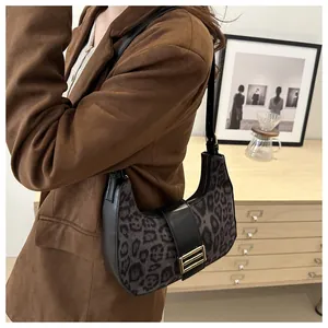 Détail du sac croissant à motif léopard porté avec un blazer marron dans un décor épuré