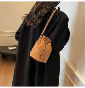 Borsa a secchiello in camoscio marrone con coulisse indossata da modella in cappotto