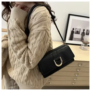 Detail of a black leather shoulder bag with a gold metal buckle and knot strap detail